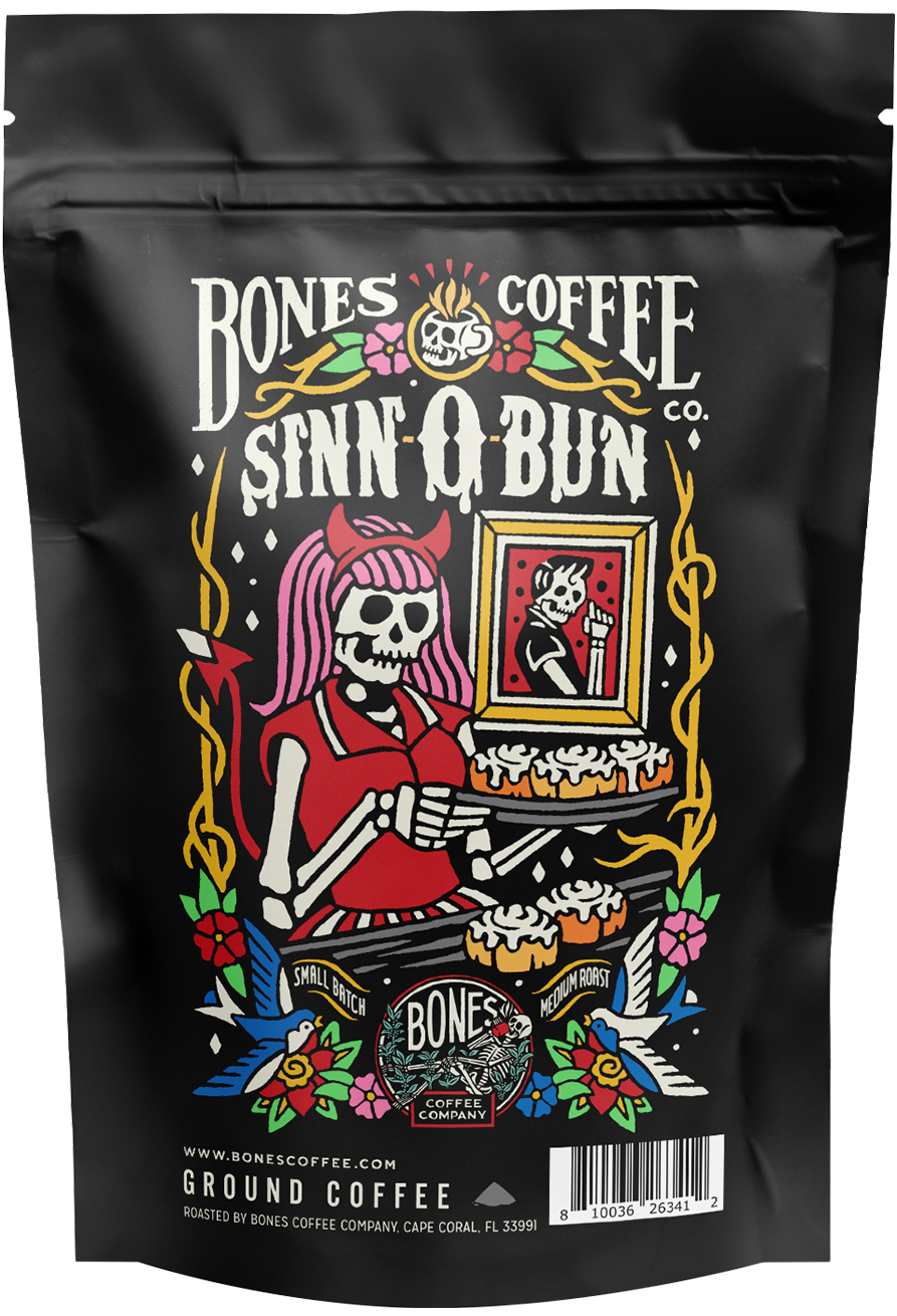 The front of a 4 ounce bag of Bones Coffee Company Sinn-o-bun coffee. Its flavor is cinnamon roll, and it has a skeleton dressed in a red and white skirt with black hair and red devil horns holding a tray of cinnamon rolls on the art.
