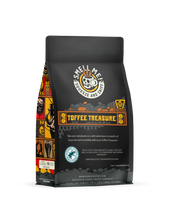 The back of a 12 ounce flavored coffee bag named Toffee Treasure. The Rain Forest Alliance page on the lower left of the back of the bag, and it says to squeeze and sniff at the top of the bag. Below the squeeze and sniff text is the name Toffee Treasure.
