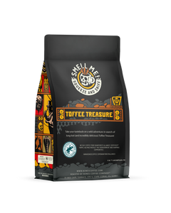The back of a 12 ounce flavored coffee bag named Toffee Treasure. The Rain Forest Alliance page on the lower left of the back of the bag, and it says to squeeze and sniff at the top of the bag. Below the squeeze and sniff text is the name Toffee Treasure.