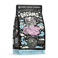 The front of a 12 ounce bag of Bones Coffee Company Cookies N’ Dreams coffee. Its flavor is cookies and vanilla ice cream, and it has a skeleton with a pillow and blanket holding a cookie and tub of ice cream on the art.