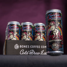 A 12-pack of cold brew lattes. Inside the pack is the Electric Unicorn cold brew lattes. A single can of this cold brew latte is on the side and has a skeleton riding a unicorn on the art. It is on top of a black table.