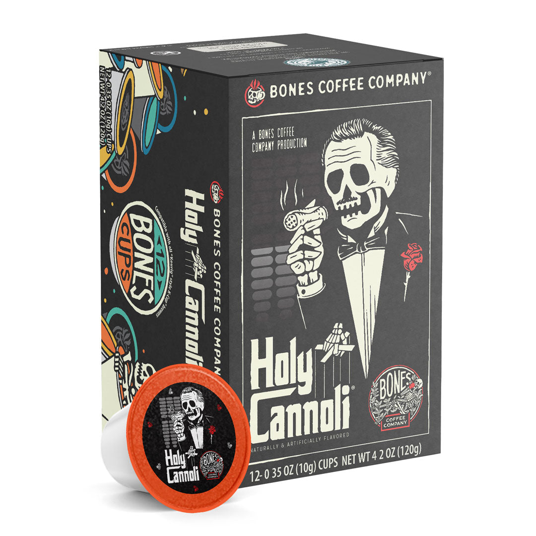 The front of the Bones Coffee Company Holy Cannoli 12 Count Bones Cups box. Its flavor is cannoli, and it has a skeleton wearing a suit with a red rose on the lapel holding a cannoli like a cigar on the art.