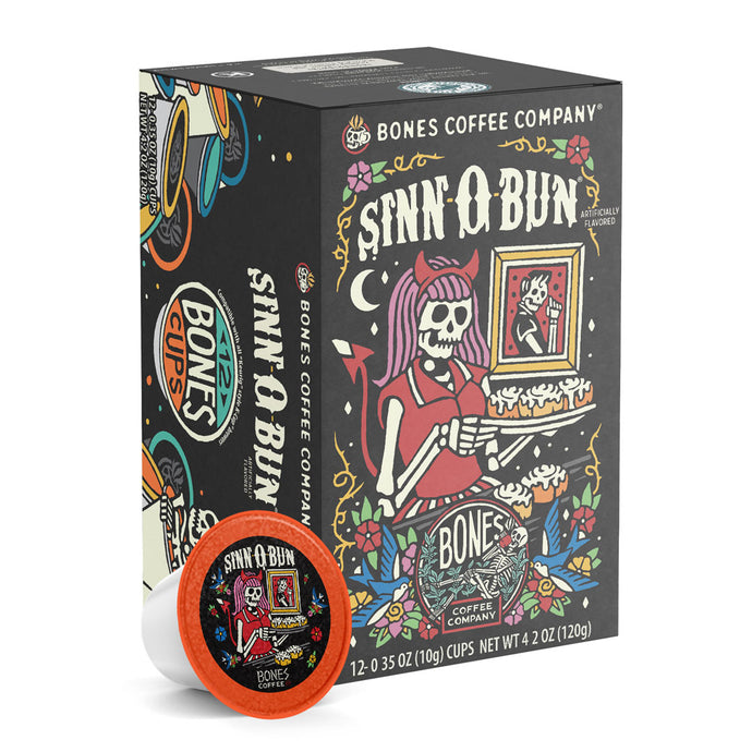 The front of the Bones Coffee Company Sinn-O-Bun 12 Count Bones Cups box. Its flavor is cinnamon bun, and it has a skeleton with pink hair wearing a horned headband holding a tray of cinnamon buns on the art.