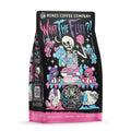 The front of a 12 ounce bag of Bones Coffee Company What the Fluff coffee. Its flavor is berry cotton candy, and it has a skeleton angrily stuffing teddy bears with cotton candy on the art.