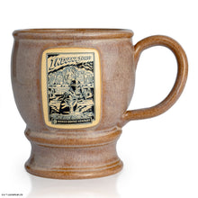 The front of the Bones Coffee Company Crusader’s Cup hand thrown mug with Indiana Jones on the golden medallion. It is inspired by Lucasfilm Indiana Jones. The mug is tan colored.