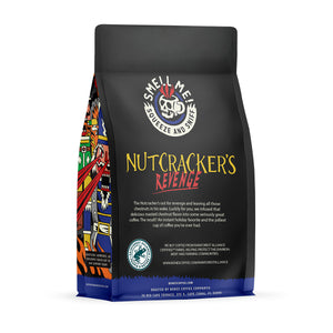 The back of a 12 ounce flavored coffee bag named Nutcracker's Revenge. The Rain Forest Alliance page on the lower left of the back of the bag and it says to squeeze and sniff at the top of the bag. Below the squeeze and sniff text is the name Nutcracker's Revenge.