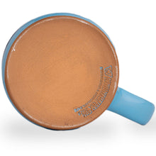 The bottom of the Shark Bite mug. It is colored ocean blue with a white glaze on top of it.