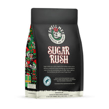 The back of a 12 ounce flavored coffee bag named Sugar Rush. The Rain Forest Alliance page on the lower left of the back of the bag and it says to squeeze and sniff at the top of the bag. Below the squeeze and sniff text is the name Sugar Rush.