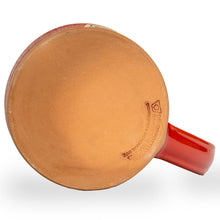 The bottom of the White Russian mug that is red colored with a sand-white glaze on top of it.