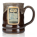 The front of the Bones Coffee Company Wookiee Cookie hand thrown mug with the Wookiee Cookie coffee art on the golden medallion. The mug is chocolate colored with a sand-white glaze on top. It is inspired by Lucasfilm’s Star Wars.