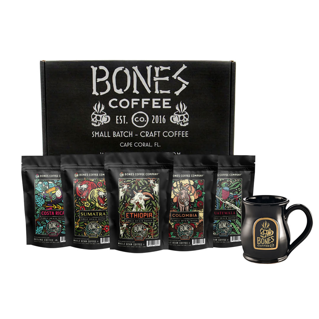 Five four ounce bags of coffee are in the front and named Guatemala, Ethiopia, Sumatra, Colombia, and Costa Rica. The box it comes in is in the back, and in front of the coffee bags is a black mug that has the Bones Coffee Company logo that has the skull that looks like a coffee mug on it.