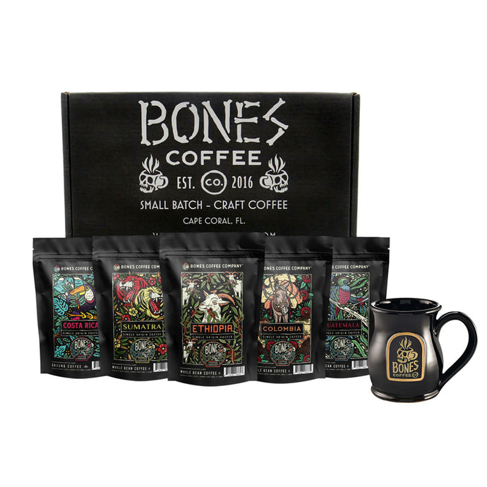 Five four ounce bags of coffee are in the front and named Guatemala, Ethiopia, Sumatra, Colombia, and Costa Rica. The box it comes in is in the back, and in front of the coffee bags is a black mug that has the Bones Coffee Company logo that has the skull that looks like a coffee mug on it.