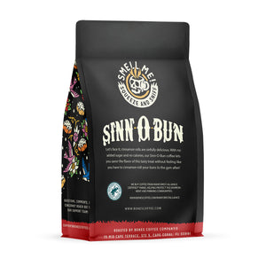 The back of a 12 ounce flavored coffee bag named Sinn-O-Bun. The Rain Forest Alliance page on the lower left of the back of the bag, and it says to squeeze and sniff at the top of the bag. Below the squeeze and sniff text is the name Sinn-O-Bun.