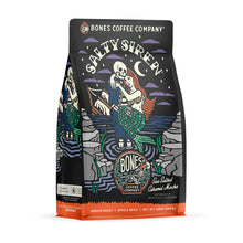 The front of a 12 ounce bag of Bones Coffee Company Salty Siren coffee. Its flavor is sea salted caramel mocha, and it has a skeleton dressed up as a sailor holding a mermaid on the art.