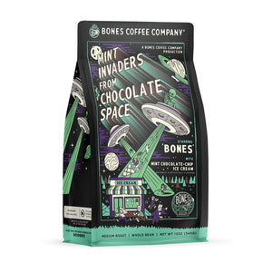 The front of a 12 ounce bag of Bones Coffee Company Mint Invaders from Chocolate Space coffee. Its flavor is mint chocolate chip ice cream, and it has green skeletons abducting ice cream and people into their UFOs on the art.