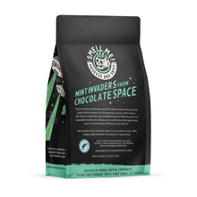 The back of a 12 ounce flavored coffee bag named Mint Invaders from Chocolate Space. The Rain Forest Alliance page on the lower left of the back of the bag, and it says to squeeze and sniff at the top of the bag. Below the squeeze and sniff text is the name Mint Invaders from Chocolate Space.