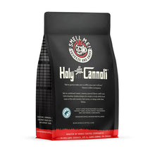 The back of a 12 oz flavored coffee bag named Holy Cannoli. The Rain Forest Alliance page on the lower left of the back of the bag, and it says to squeeze and sniff at the top of the bag. Below the squeeze and sniff text is the name Holy Cannoli.