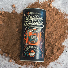 A tin of drinking chocolate mix that has marshmallows in it. It's on top of a mound of drinking chocolate mix.