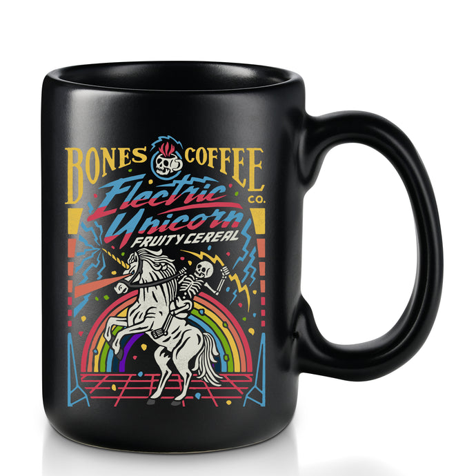 The front of the Electric Unicorn mug. It is colored black and has art of a skeleton riding a unicorn in front of a rainbow on it.