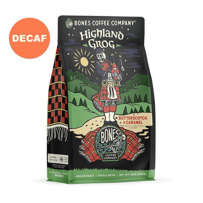 The front of a 12 ounce bag of Bones Coffee Company Highland Grog coffee. Its flavor is caramel and butterscotch, and it has a skeleton wearing a kilt playing bagpipes on a hill on the art. There is a sticker that says decaf.