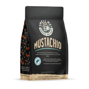 The back of a 12 ounce flavored coffee bag named Mustachio. The Rain Forest Alliance page on the lower left of the back of the bag, and it says to squeeze and sniff at the top of the bag. Below the squeeze and sniff text is the name Mustachio.
