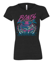 The front of the women's Retro Summer tee shirt. They're colored black and has art of a skeleton sipping coffee in a hammock between two palm trees before a retro colored sun.