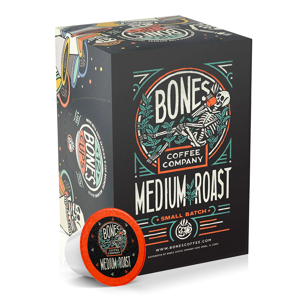 The front of the Bones Coffee Company Medium Roast 12 Count Bones Cups box. It has the Bones Coffee Company logo that has a skeleton sipping coffee, lounging on greenery around it on the art.