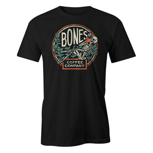 The men's classic Bones Coffee Company logo tee shirt. The tee shirt is black and the logo has a skeleton sipping coffee resting on greenery.
