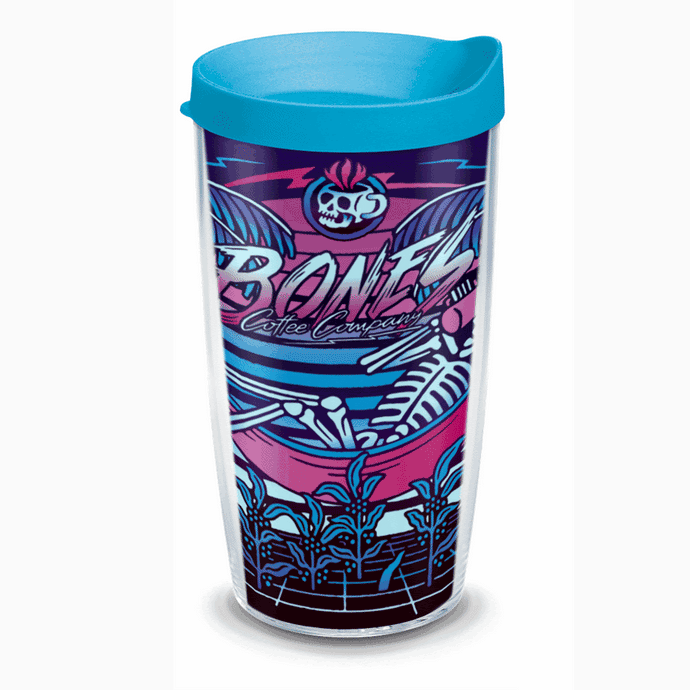A tumbler with a blue lid. The art on the tumbler shows a retro-style art of a skeleton drinking coffee in a hammock between palm trees before a retro-colored sun.