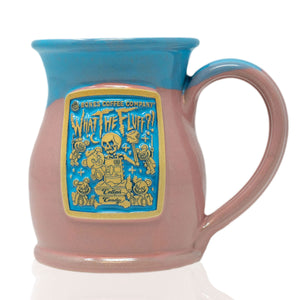 The front of the Bones Coffee Company What the Fluff hand thrown mug with the What the Fluff coffee art on the golden medallion. The mug is cotton candy colored and has a powder-blue glaze on top of it.